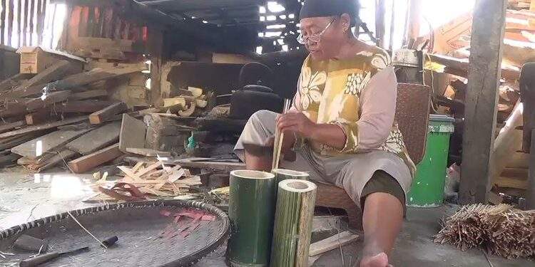Karmini (63) pengrajin tusuk sate asal Kabupaten Bandung, membuat tusuk sate untuk memenuhi kebutuhan pasar jelang Idul Adha, (KOMPAS.COM/M. Elgana Mubarokah)